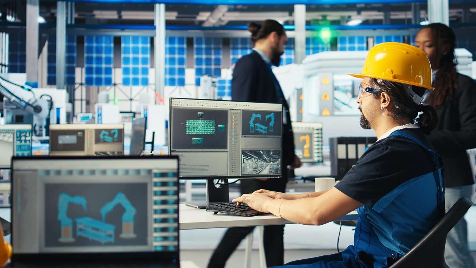 Person wearing protective helmet sitting at a computer.